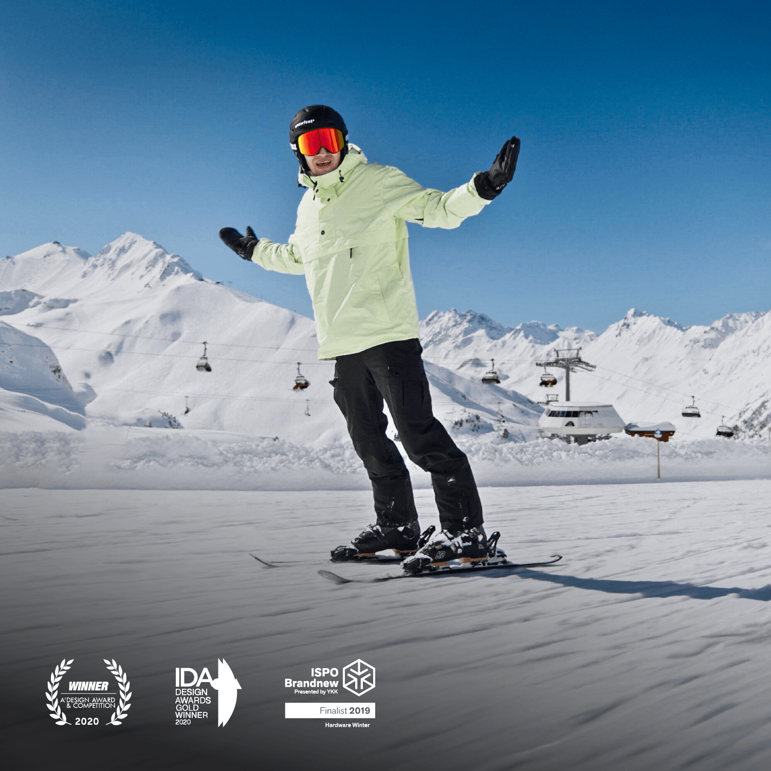Person snowboarding on a snowy slope with mountains and ski lifts in the background. Skiblades Snowfeet* 99cm